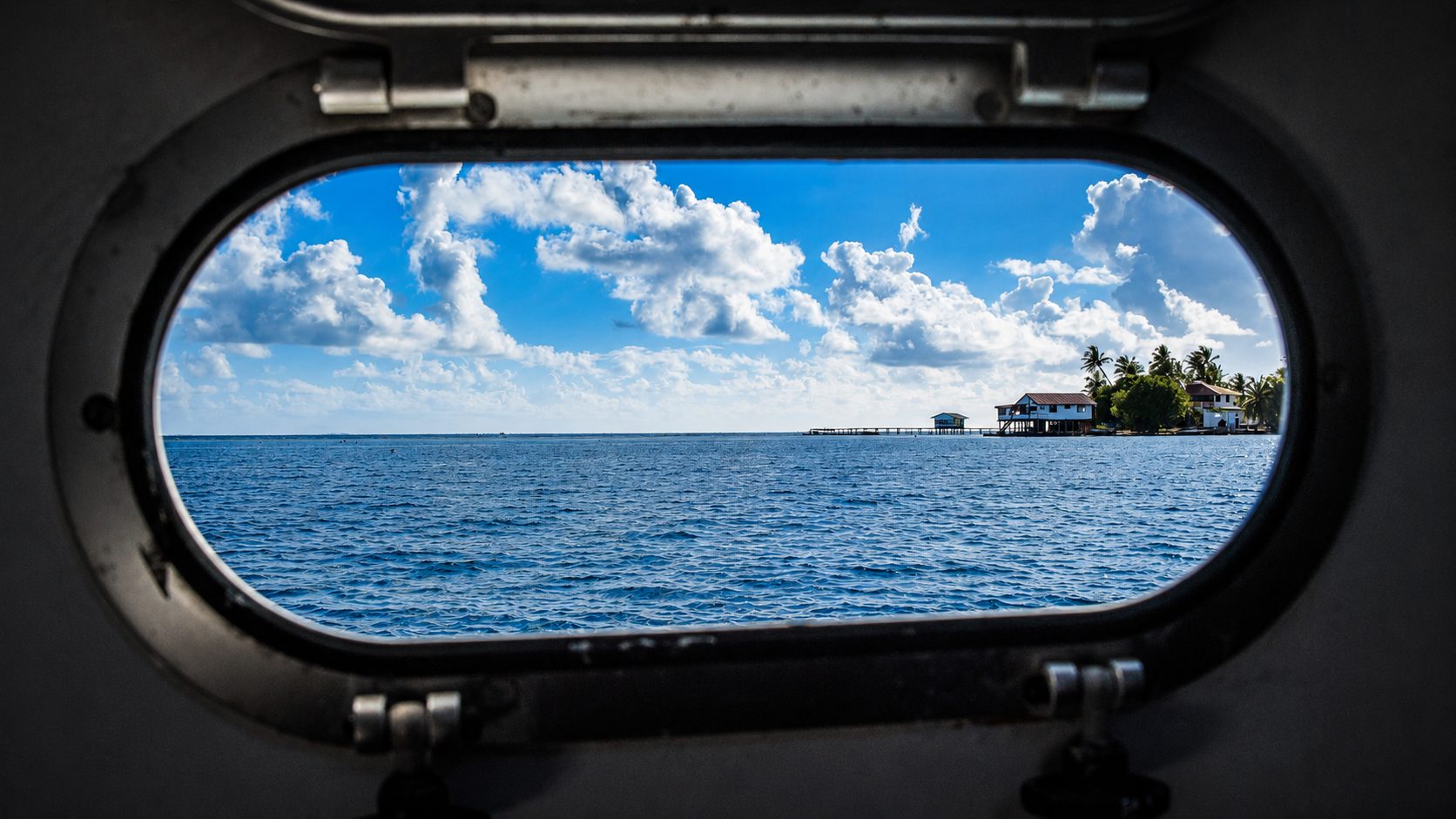 Lagoon and overwater houses seen through a ship porthole in French Polynesia